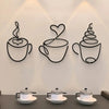 A set of three black iron wall art pieces shaped like coffee cups, featuring heart and swirl designs.