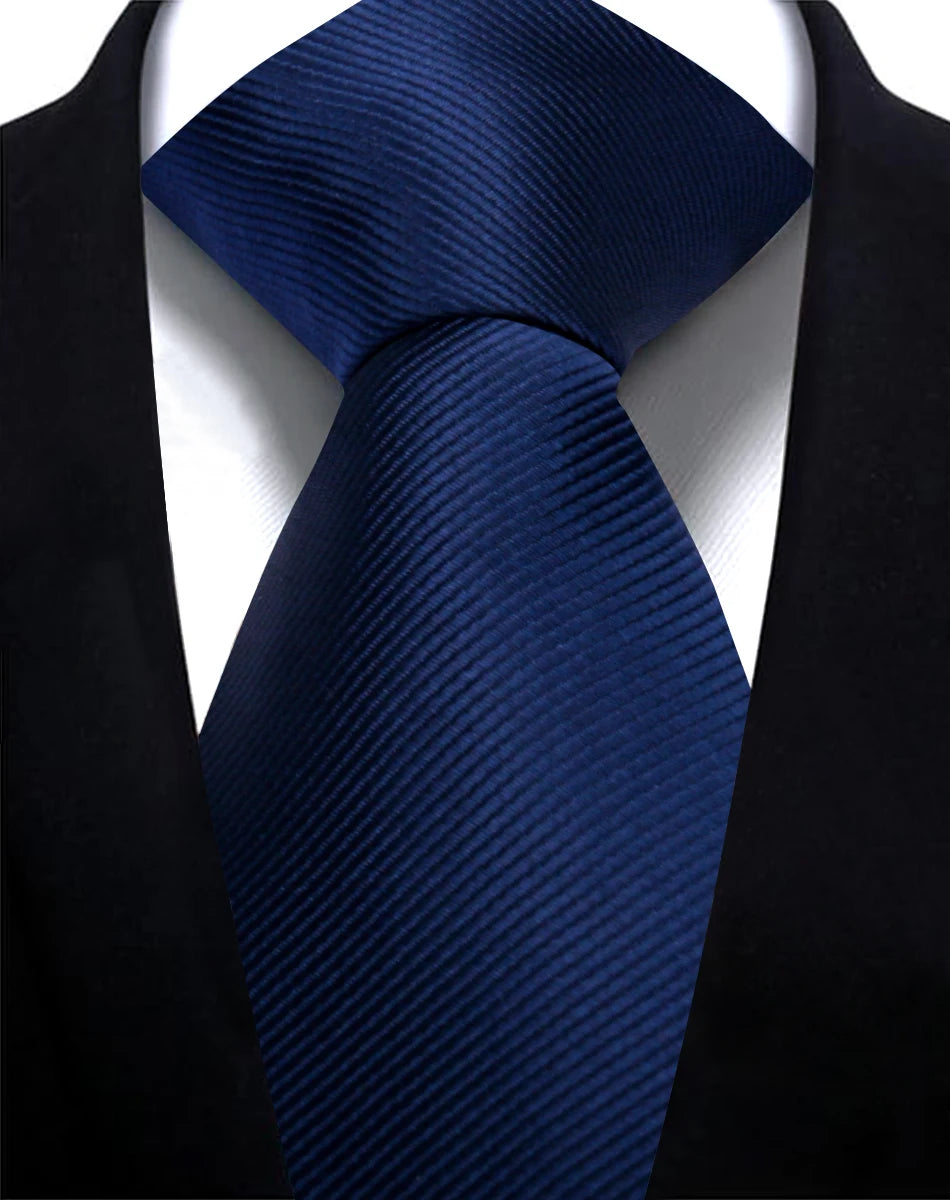 A dark blue silk necktie with a diagonal stripe pattern worn against a black suit jacket.