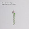 A small, translucent green glass flower with a pink petal is shown against a white background.