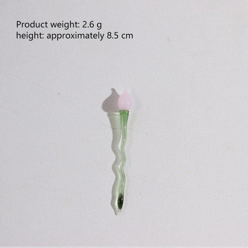 A small, translucent green glass flower with a pink petal is shown against a white background.