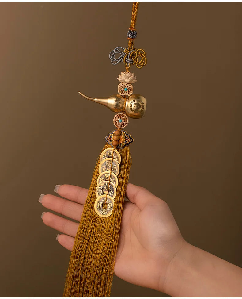 A brass gourd and five emperor coins hanging ornament on a gold thread.