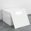 A stack of white faux marble 3D self-adhesive wall tiles or wallpaper displayed on a gray floor.
