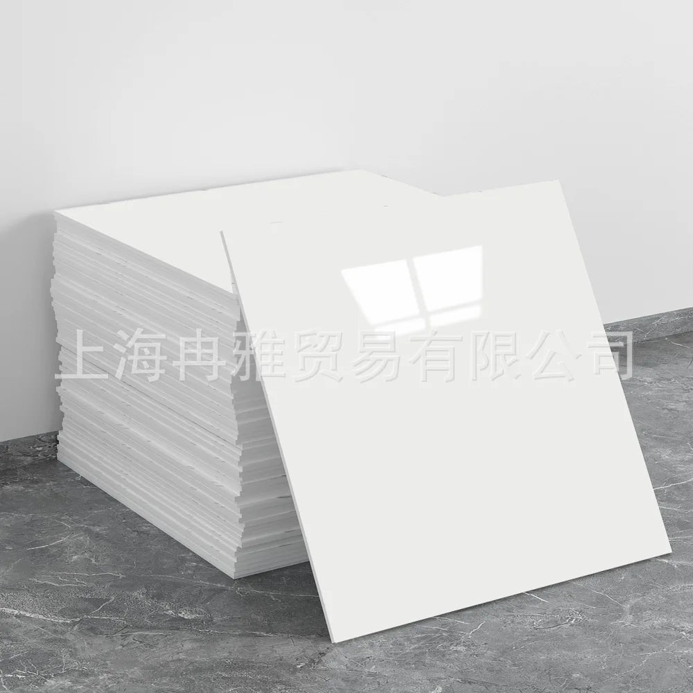 A stack of white faux marble 3D self-adhesive wall tiles or wallpaper displayed on a gray floor.
