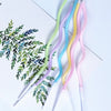 A collection of curved metallic birthday cake candles in pastel colors, including green, blue, yellow, and pink.