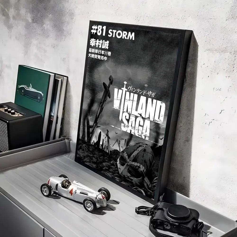 A poster of Vinland Saga anime featuring a dramatic scene, displayed next to a box and on a white surface.