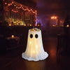An adjustable glowing ghost treat bucket filled with colorful Halloween candies sits on a wooden floor in a dimly lit bar set