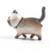 A small, light gray and white 3D cartoon cat figurine used as a refrigerator magnet.