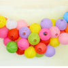 A colorful arrangement of round paper lanterns in various shades including yellow, pink, orange, purple, and green.