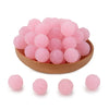 A pile of pink textured resin beads for jewelry making in a wooden bowl.