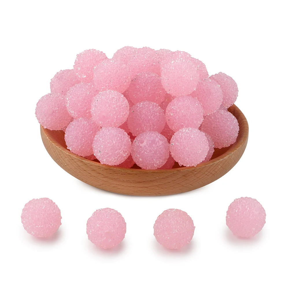 A pile of pink textured resin beads for jewelry making in a wooden bowl.