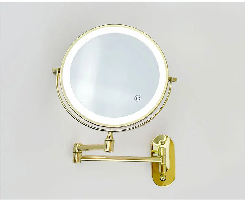 A round, illuminated makeup mirror with a gold-toned mounting bracket and USB charging feature.