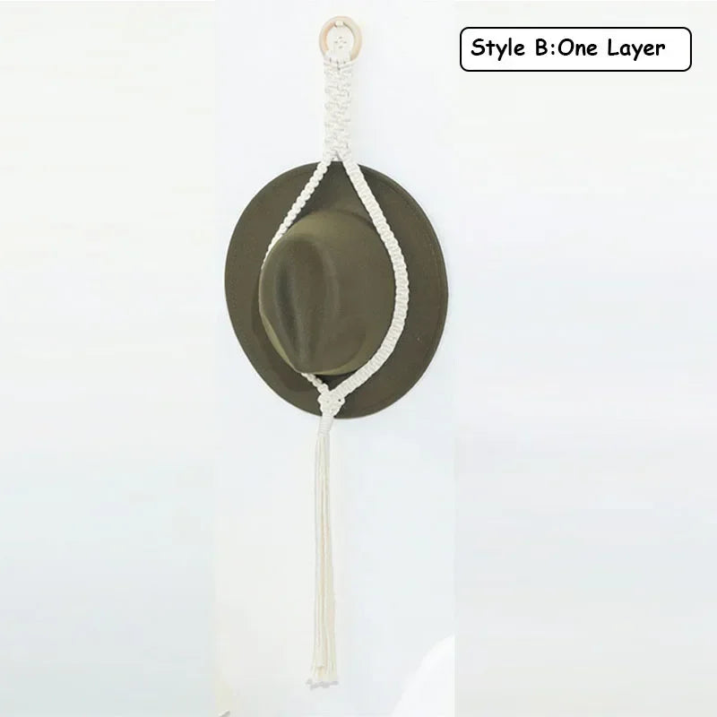 A handmade macrame hat organizer with a wooden dowel is shown as a single layer boho wall hanging.