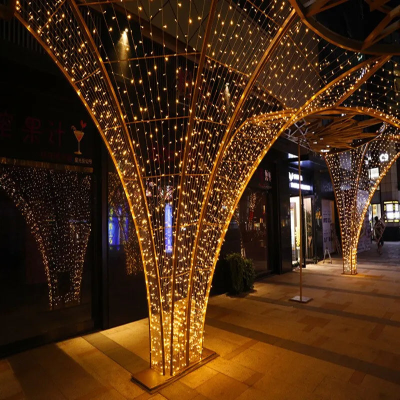 Instalación decorativa con una gran estructura de árbol dorado cubierta de luces LED blancas cálidas.
