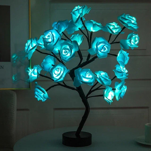 Escultura de árbol oscuro con flores de rosa azules brillantes, funcionando como lámpara de mesa LED.