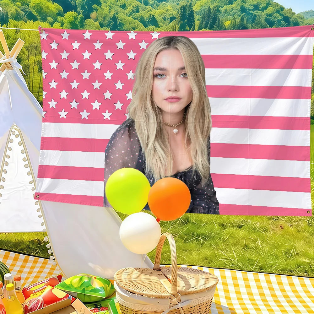 A woman in a dark top stands in front of a large American flag banner with red and white stripes and stars, surrounded by yel