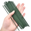 A hand holds a bundle of thin, green artificial flower stems for DIY floral decor.