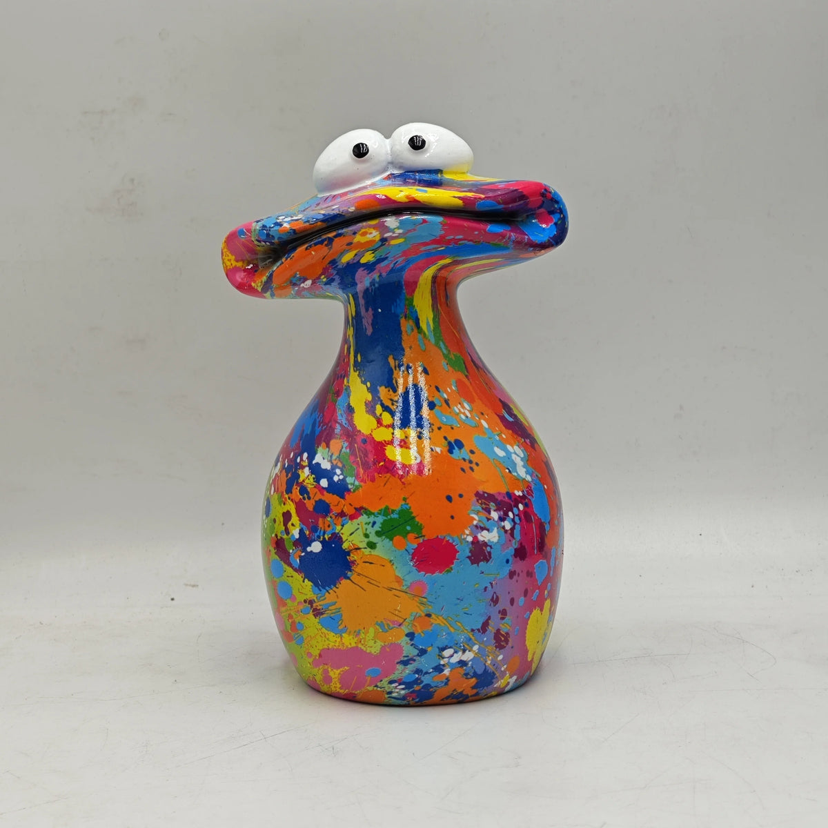 A colorful resin figurine shaped like a frog with an open mouth and white eyes.