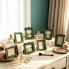 A collection of vintage baroque resin picture frames, perfume bottles, and rose petals displayed on a light surface.