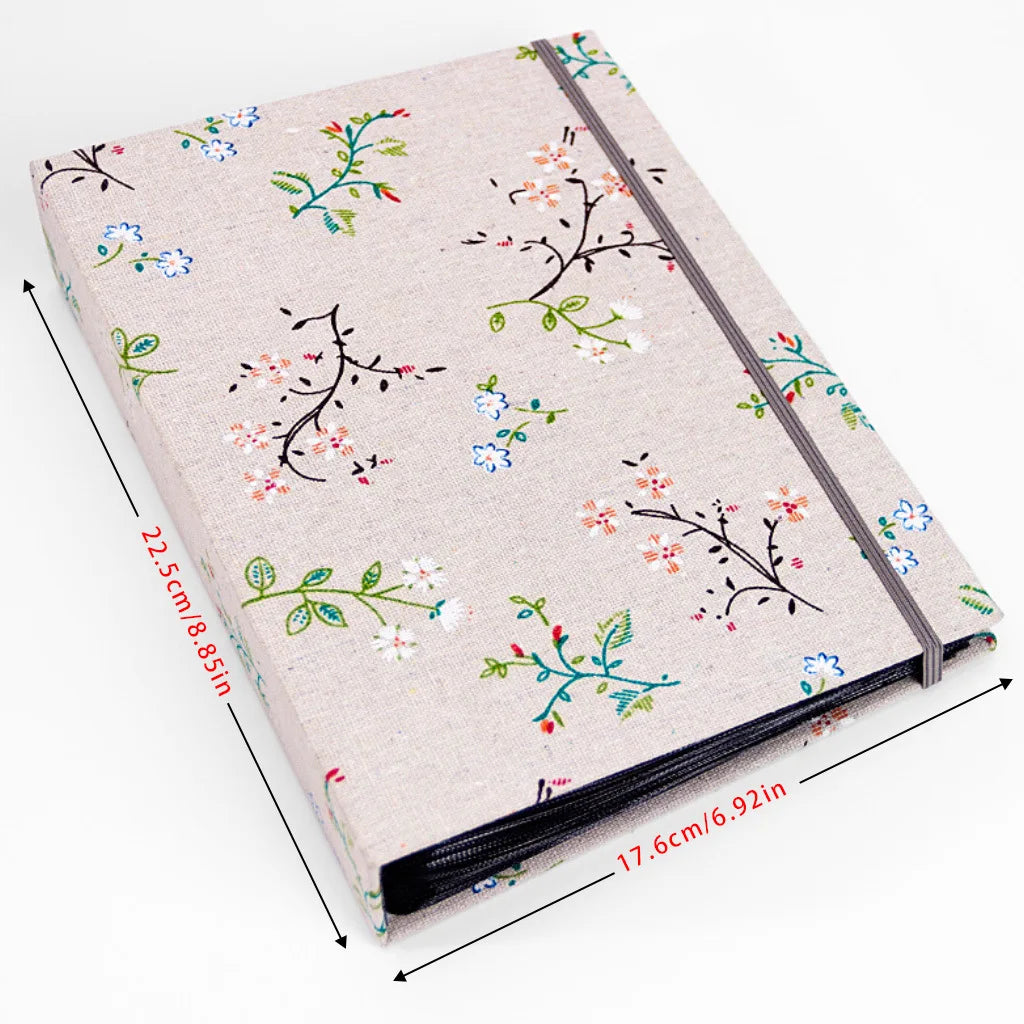 Beige Fotoalbum mit schwarzem Reißverschluss und floraler Stickerei auf dem Cover.