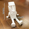 A white 3D printed Moai statue figurine with movable joints shown against a wooden background.