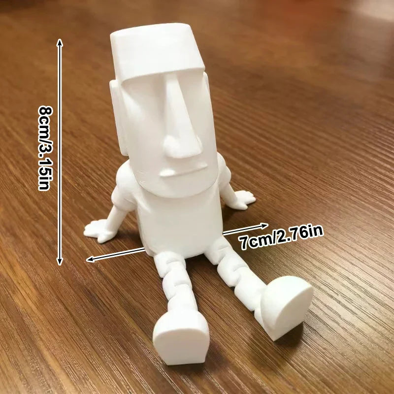 A white 3D printed Moai statue figurine with movable joints shown against a wooden background.