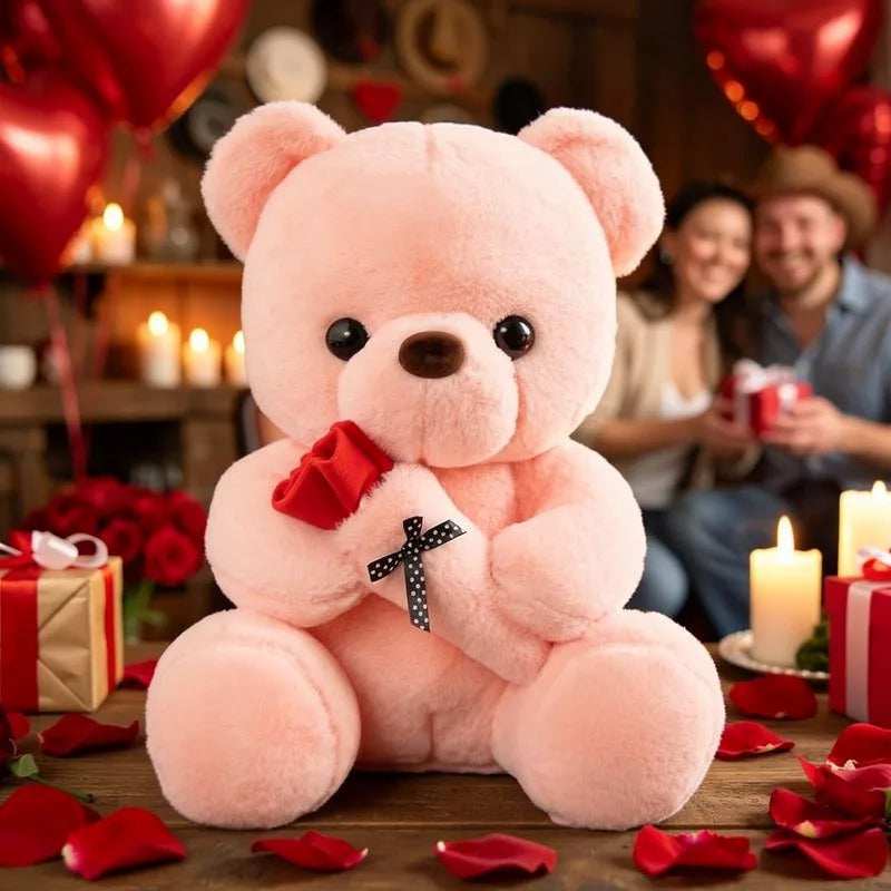 A pink bear plush toy sitting on a wooden surface surrounded by red rose petals and gifts.
