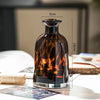 A dark amber glass vase with a narrow neck and rounded body sits on a white surface.
