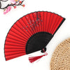 A red folding fan with black ribs and a bamboo handle is shown against a white background.