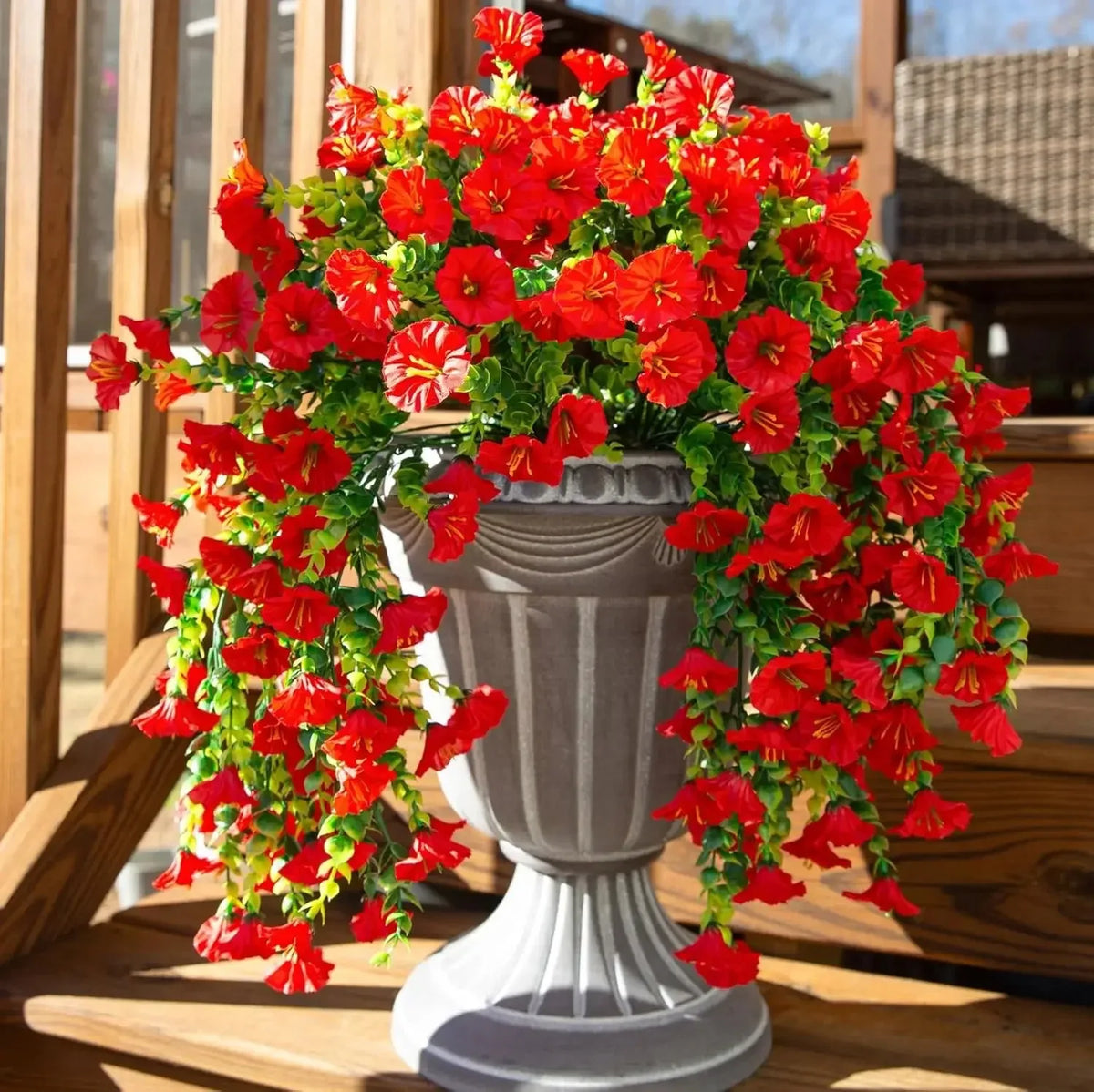 A vibrant arrangement of artificial red morning glory hanging vines in a gray urn for garden decor.
