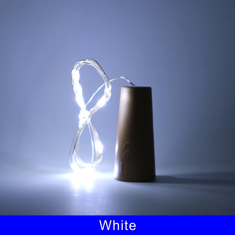 A glowing white LED wine bottle cork light is shown next to a brown bottle.