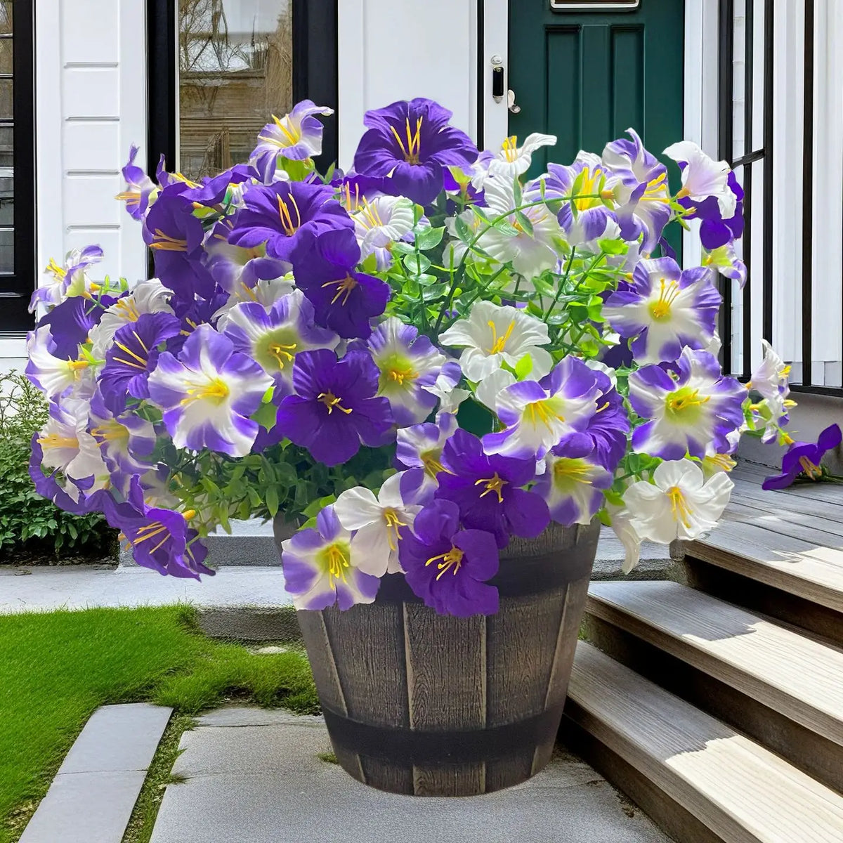 A vibrant bouquet of artificial silk purple and white flowers in a dark planter on a porch.