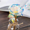 A close-up of a realistic white artificial rose with iridescent blue and yellow tones displayed in a glass jar.