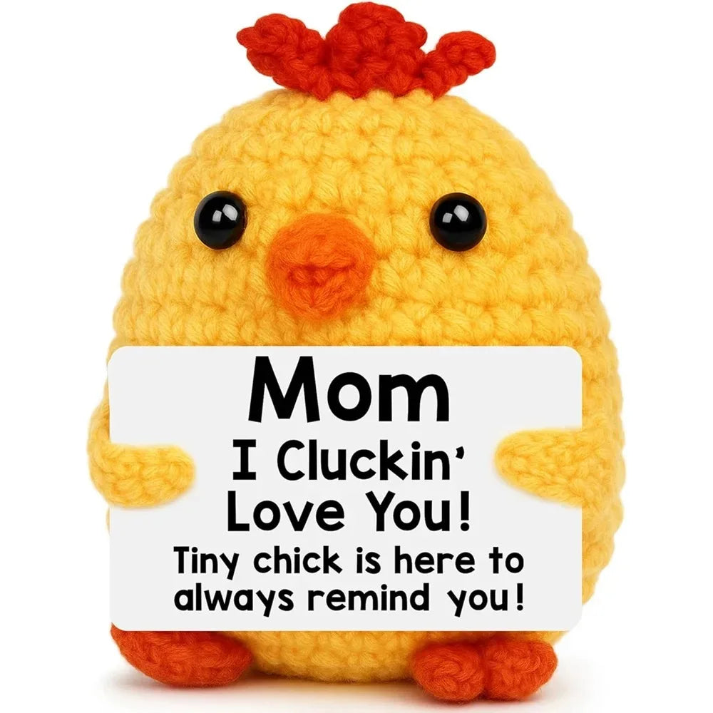 A handcrafted yellow crochet chick doll with an orange beak and red fluff, featuring a sign that says Mom I Cluckin' Love You