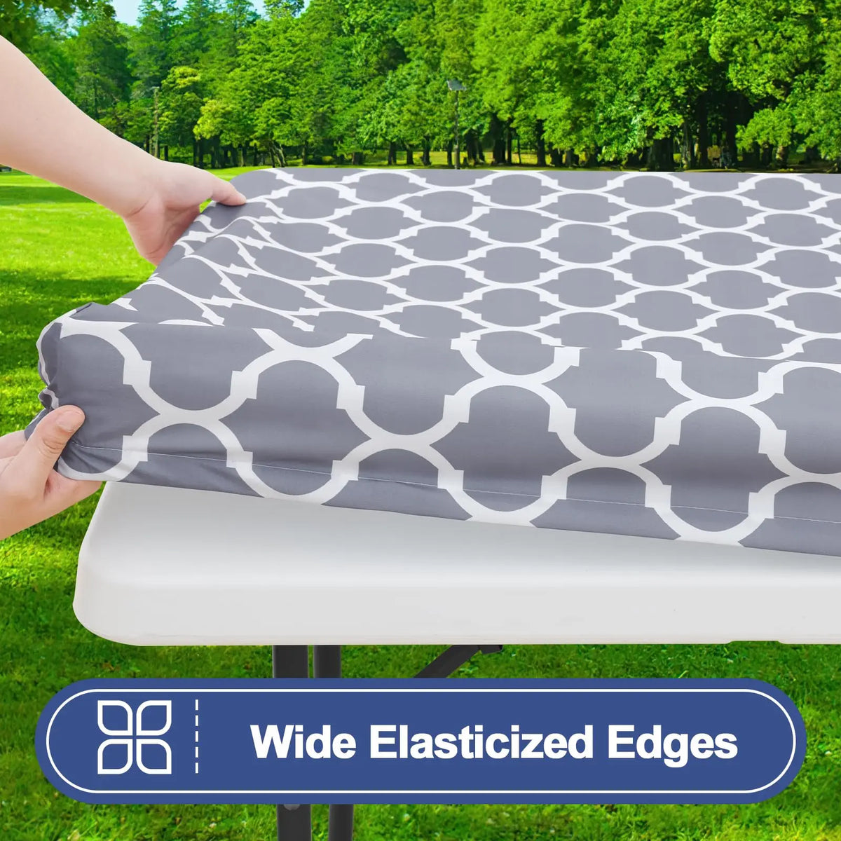 A gray waterproof elastic fitted tablecloth is being placed on a white table outdoors.