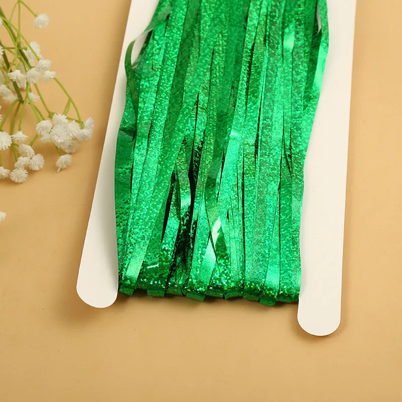 Green metallic tinsel foil fringe curtain backdrop for parties displayed on a white card.
