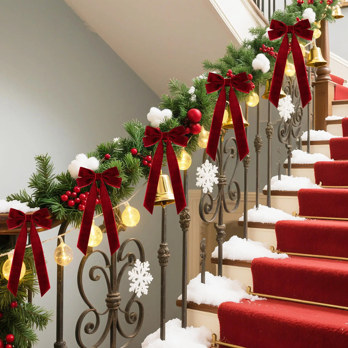 A staircase decorated with evergreen garlands and red velvet bows, accented by gold bells and white snow.