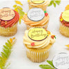 A display of yellow cupcake liners topped with mirror acrylic happy birthday cake toppers and frosting.