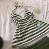 A white and black striped sleeveless top laid flat on a light pink surface.
