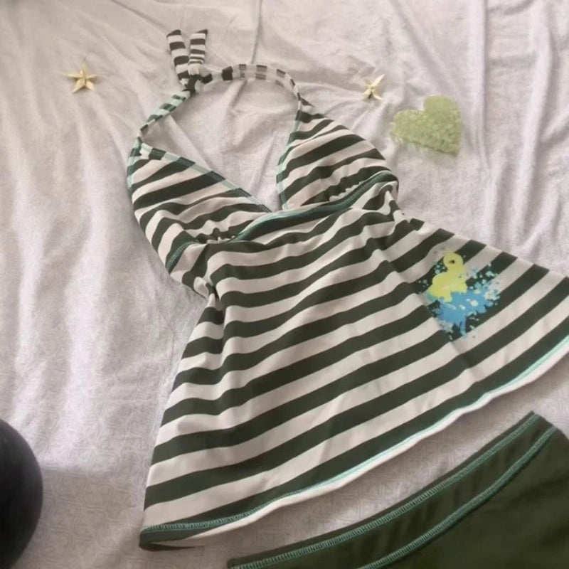 A white and black striped sleeveless top laid flat on a light pink surface.