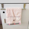 Serviette rose en duvet, suspendue sur un porte-serviettes en acier inoxydable.