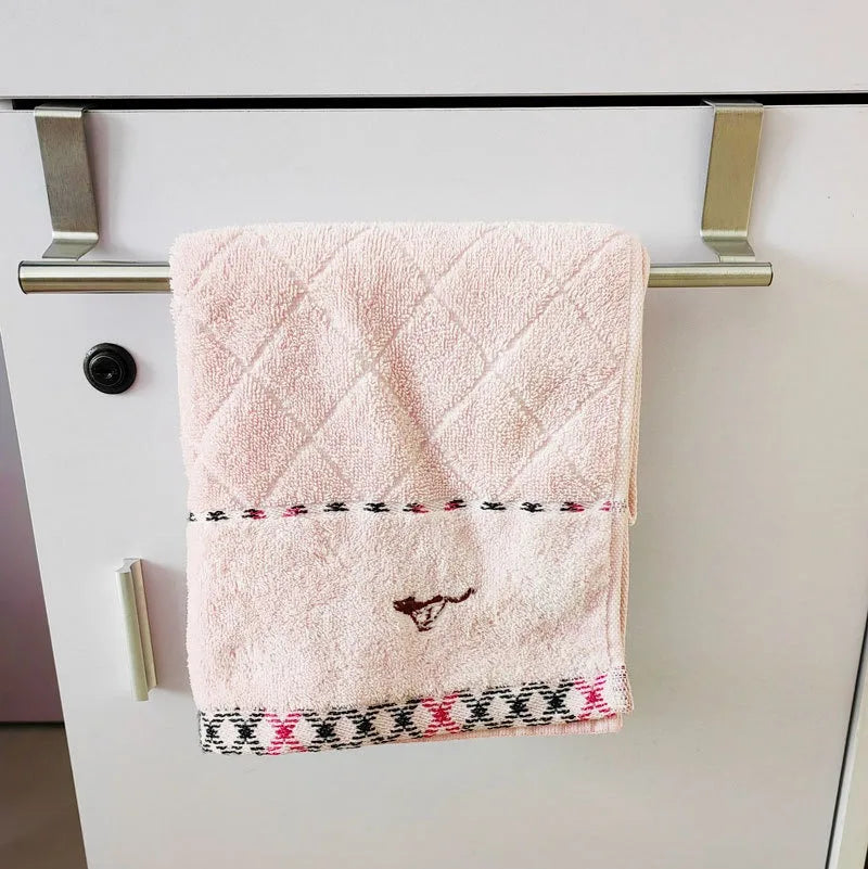 Serviette rose en duvet, suspendue sur un porte-serviettes en acier inoxydable.
