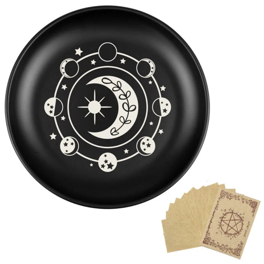 Assiette décorative noire avec motif céleste blanc : lune, étoiles et feuillage.