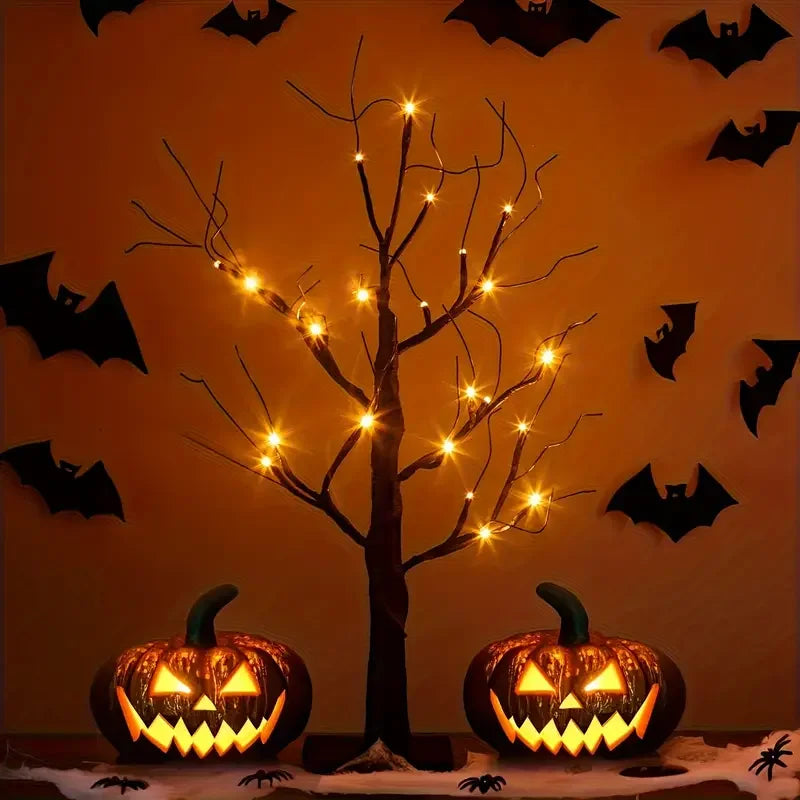 A glowing Halloween birch tree lamp with LED lights stands next to carved pumpkins on a surface.