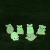 A collection of luminous green glow-in-the-dark resin pig decorations resting on dark green grass.