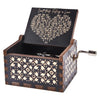 A dark wooden hand-cranked music box with an engraved lid featuring a poem about falling in love.
