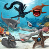 A collection of 3D printed sea monster fidget toys including a dark green eel, orange shark, blue shark, and gray sea creatur