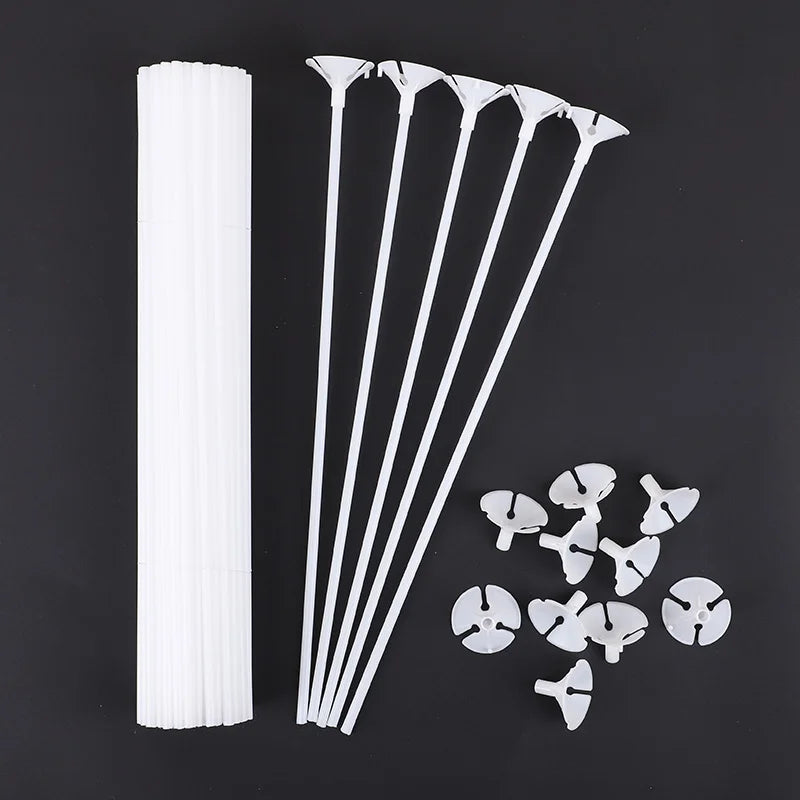White macaron balloon sticks with holder cups arranged diagonally on a dark background