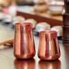 A handcrafted pure copper vintage mug with a tapered shape is shown on a wooden surface.