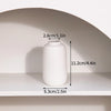 A white ceramic bud vase is displayed on a shelf, showing its dimensions.