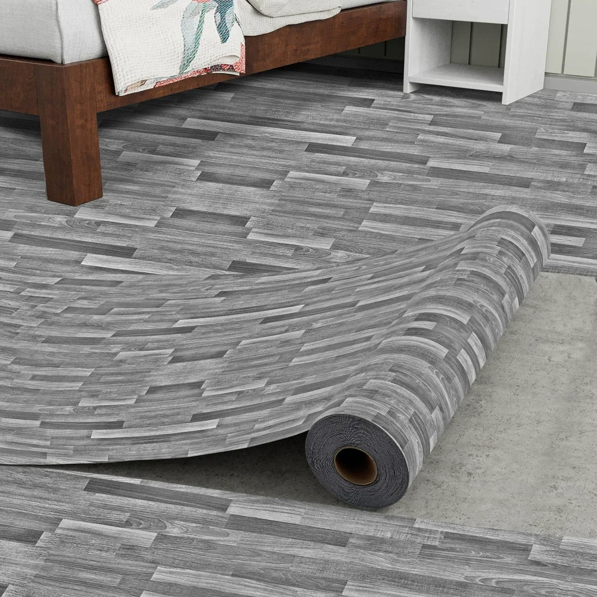 Roll of realistic wood grain floor stickers laid out on a concrete floor.